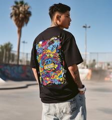 Person wearing a black t-shirt with colorful graphics, standing in an outdoor setting with palm trees.