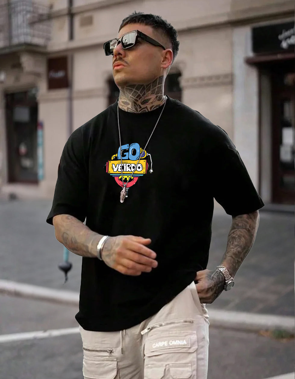 Man wearing a black t-shirt with a colorful logo and text, standing on a street.